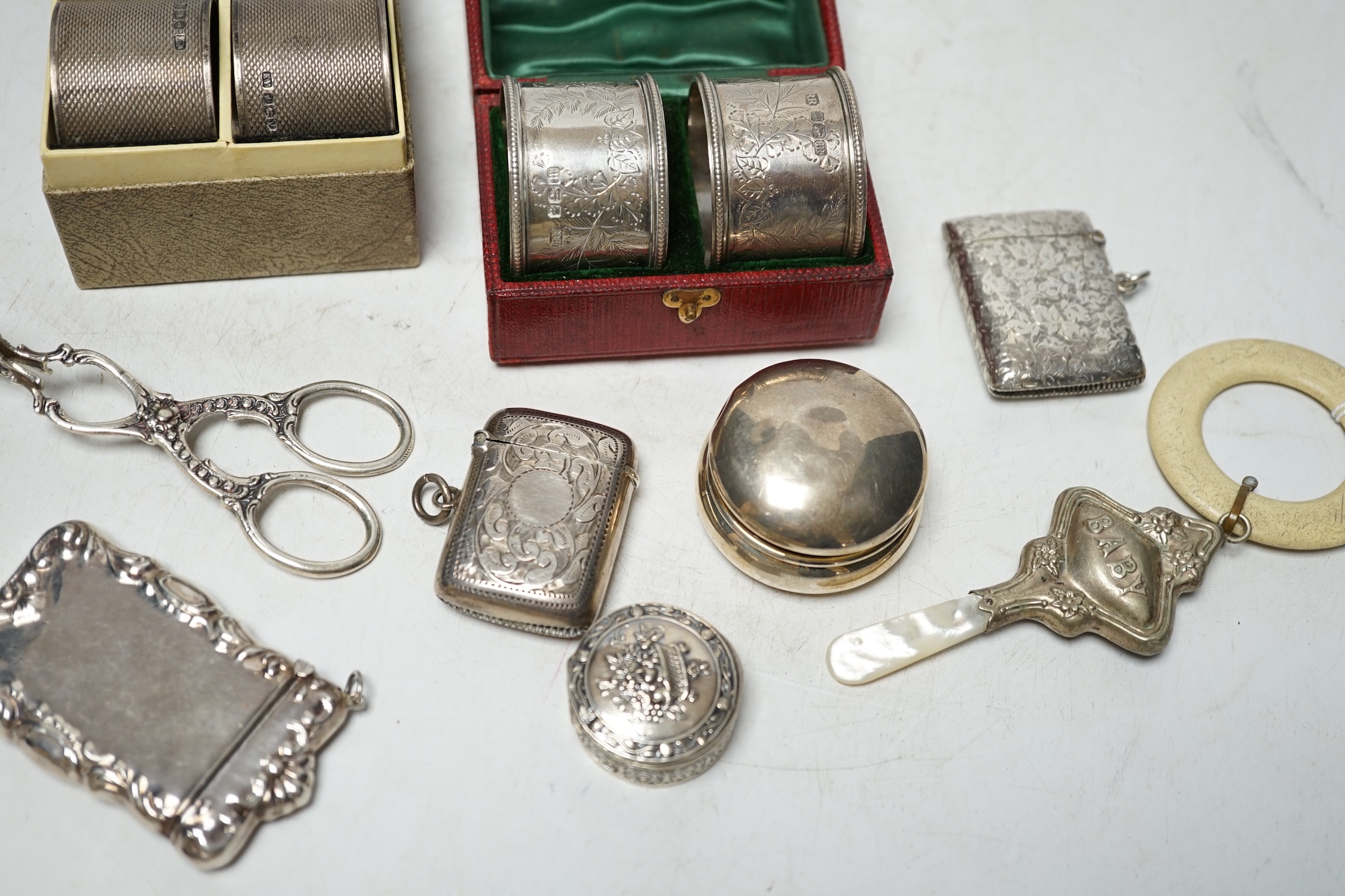 A cased pair of Edwardian engraved silver napkin rings, one other pair of engine turned silver napkin rings and sundry small items of silver, white metal and 925 including vesta cases, child's rattle, etc. Condition - po